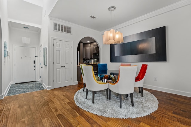 dining space with visible vents, arched walkways, and wood finished floors