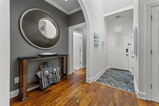 foyer with baseboards, wood finished floors, arched walkways, and ornamental molding