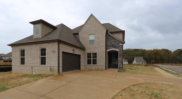 view of front facade with an attached garage, brick siding, driveway, and a shingled roof