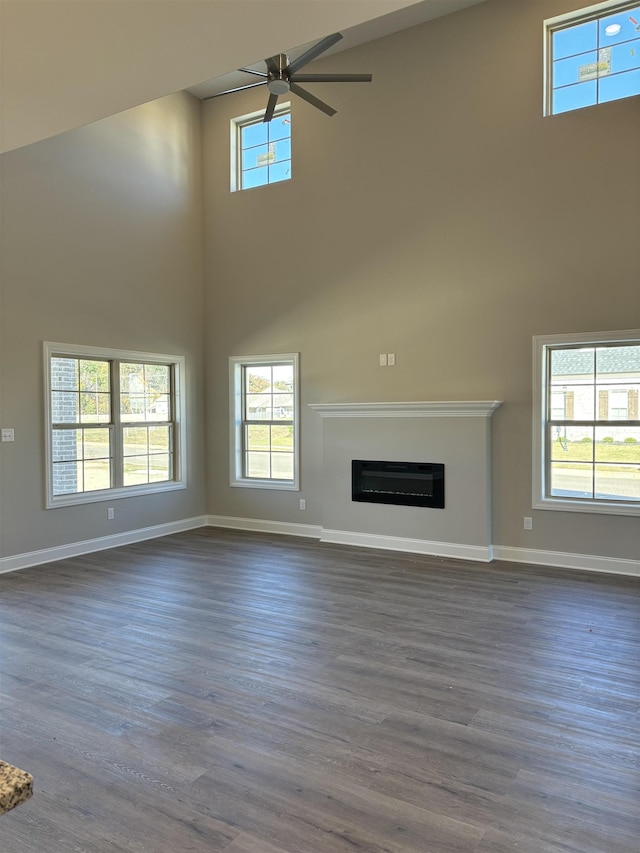 unfurnished living room featuring dark wood finished floors, baseboards, and ceiling fan