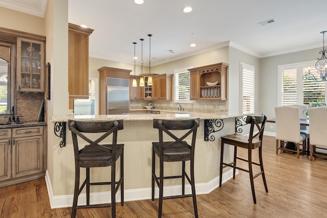 kitchen featuring a chandelier, a peninsula, built in refrigerator, and light wood-type flooring