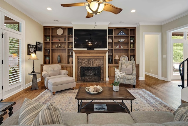 living area with baseboards, ornamental molding, a wealth of natural light, and wood finished floors