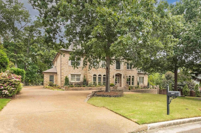 view of front of home featuring brick siding, driveway, and a front lawn