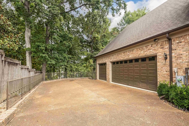 garage featuring driveway and fence