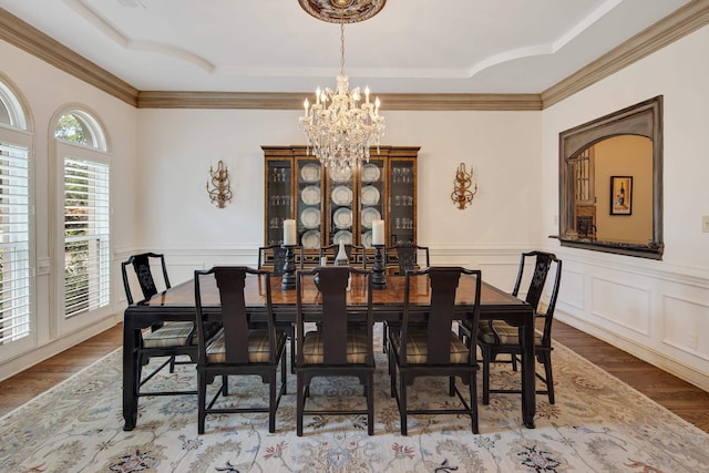 dining room with a raised ceiling, a wainscoted wall, and wood finished floors