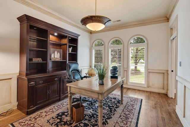 office space featuring light wood-style floors, wainscoting, visible vents, and crown molding