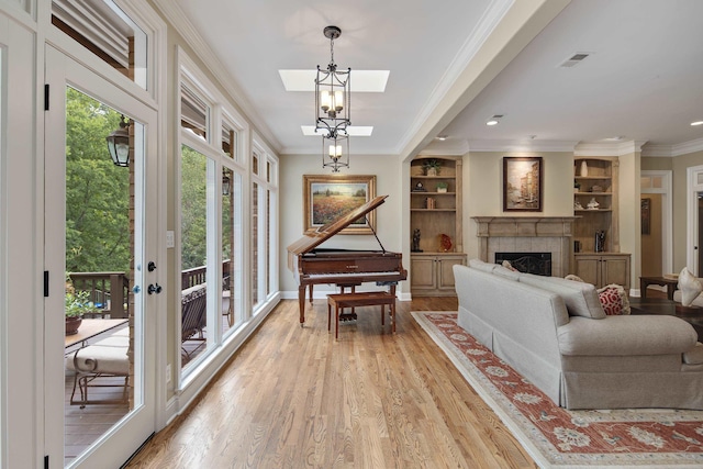 living area with crown molding, visible vents, light wood-type flooring, baseboards, and a tile fireplace