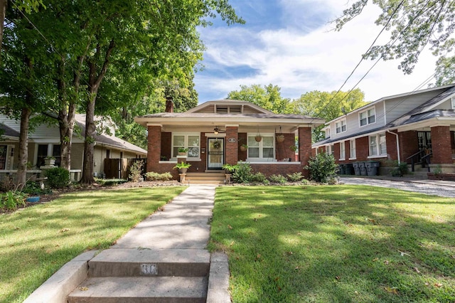 bungalow with brick siding, covered porch, a front yard, and ceiling fan