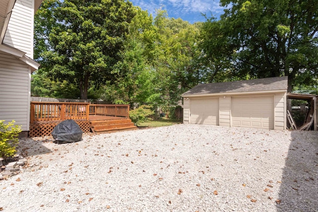 exterior space with a garage, a wooden deck, and an outbuilding