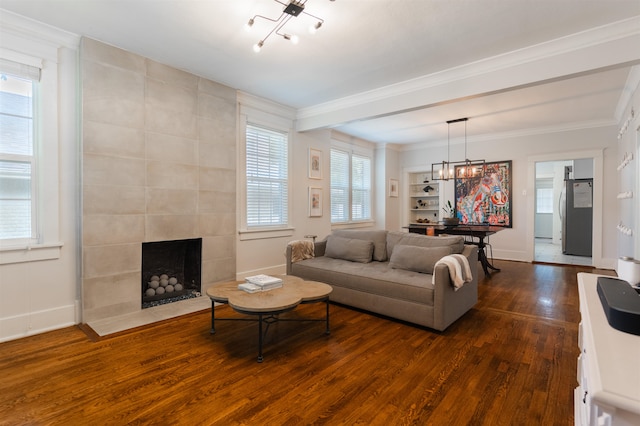 living room featuring an inviting chandelier, a fireplace, crown molding, and dark wood-type flooring