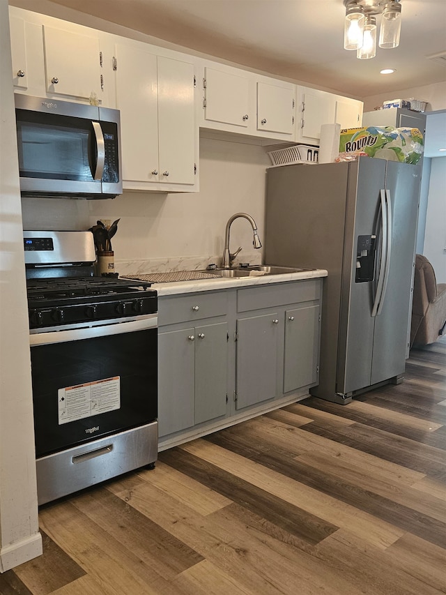 kitchen featuring gray cabinets, white cabinetry, dark hardwood / wood-style flooring, sink, and appliances with stainless steel finishes