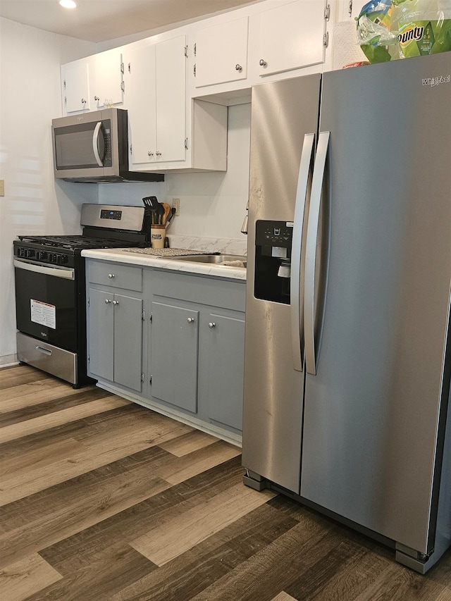 kitchen with gray cabinets, white cabinetry, stainless steel appliances, and dark hardwood / wood-style floors