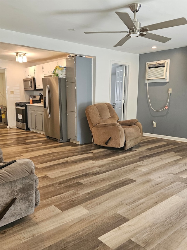 living room featuring a wall mounted AC, wood-type flooring, and ceiling fan