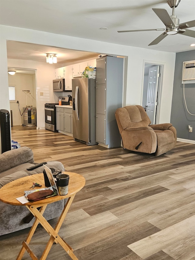 living room with ceiling fan, a wall unit AC, and light hardwood / wood-style floors