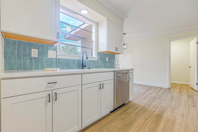 kitchen with a textured ceiling, light hardwood / wood-style floors, stainless steel dishwasher, decorative backsplash, and ornamental molding