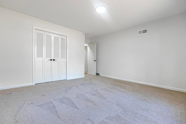 unfurnished bedroom with light colored carpet and a closet