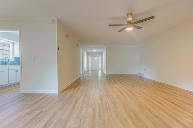 empty room featuring crown molding, light hardwood / wood-style flooring, ceiling fan, and sink