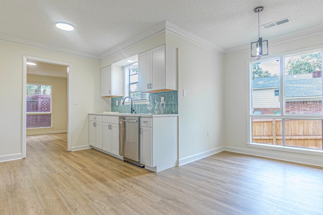 kitchen featuring decorative light fixtures, light hardwood / wood-style floors, crown molding, stainless steel dishwasher, and white cabinetry