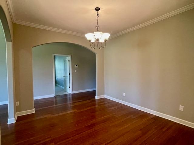 unfurnished room featuring ornamental molding, dark wood-type flooring, and a chandelier