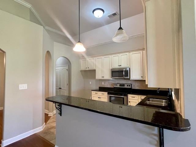 kitchen featuring dark stone counters, decorative light fixtures, stainless steel appliances, kitchen peninsula, and sink