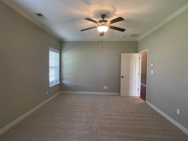 carpeted empty room with ceiling fan and crown molding