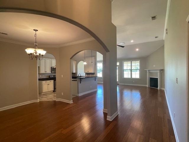 unfurnished living room with crown molding, dark hardwood / wood-style flooring, and an inviting chandelier