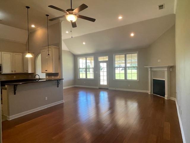 unfurnished living room with ceiling fan, dark hardwood / wood-style floors, sink, and high vaulted ceiling