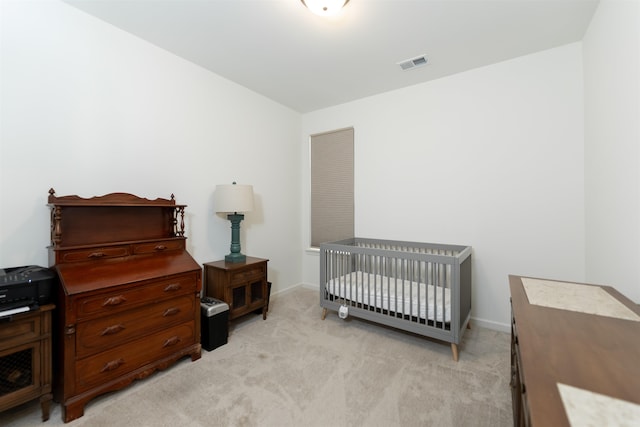 bedroom featuring a crib and light colored carpet