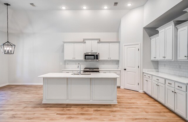 kitchen featuring a center island with sink, stainless steel appliances, sink, and light hardwood / wood-style floors