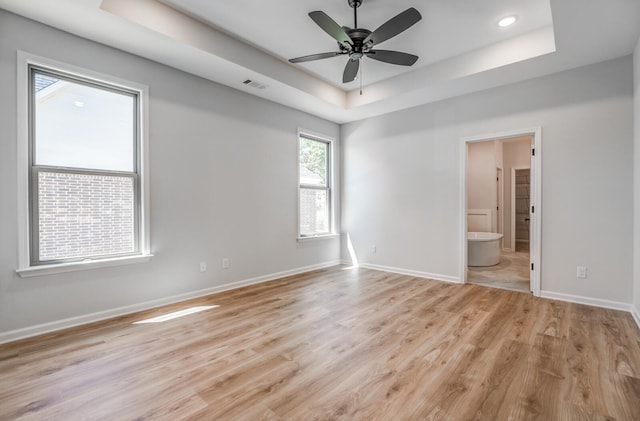 spare room featuring ceiling fan, a tray ceiling, and light hardwood / wood-style floors