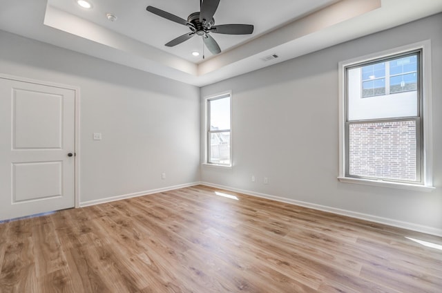 empty room featuring a tray ceiling, baseboards, and visible vents