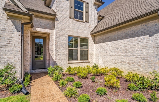 property entrance with brick siding and a shingled roof