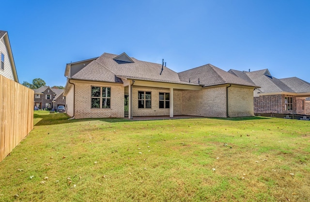 rear view of property with a yard, brick siding, and a shingled roof