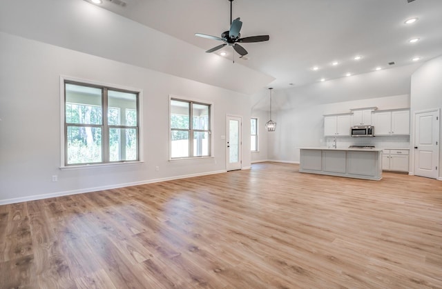 unfurnished living room featuring recessed lighting, a ceiling fan, light wood-type flooring, and baseboards