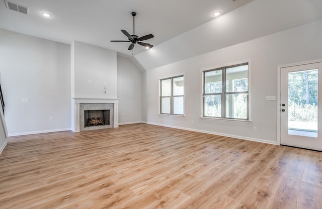 unfurnished living room featuring light hardwood / wood-style flooring, ceiling fan, a tile fireplace, and vaulted ceiling