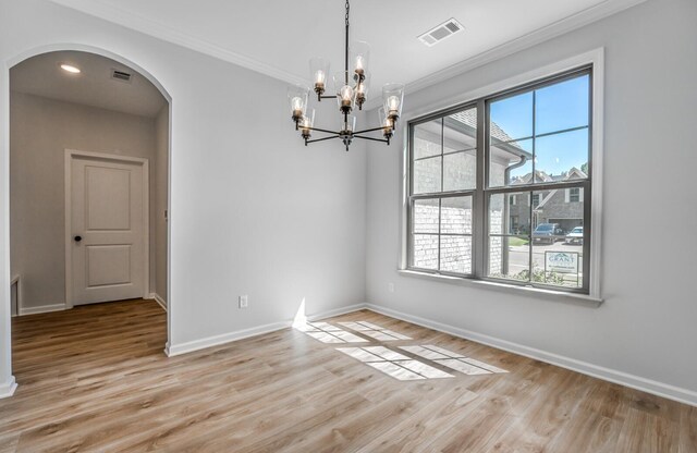 unfurnished dining area with ornamental molding, a chandelier, and light hardwood / wood-style floors