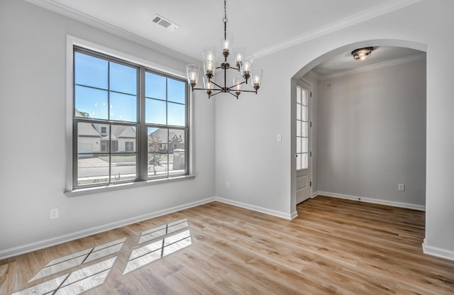 spare room featuring visible vents, light wood-style flooring, ornamental molding, arched walkways, and baseboards