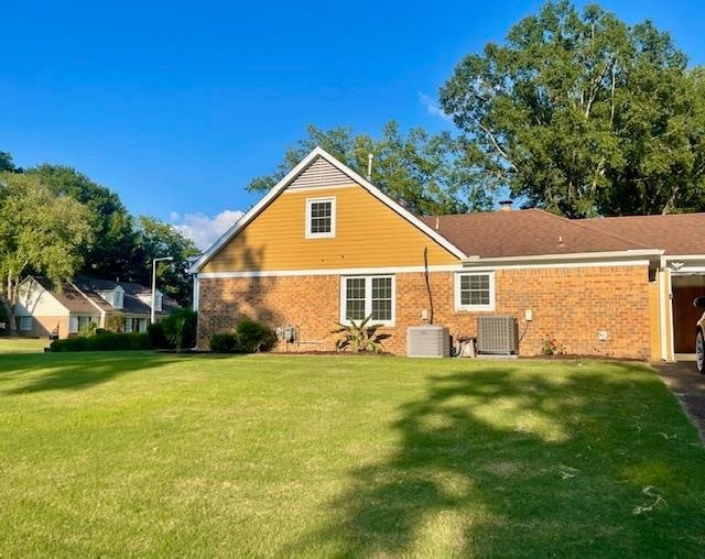 rear view of house with a lawn and central AC