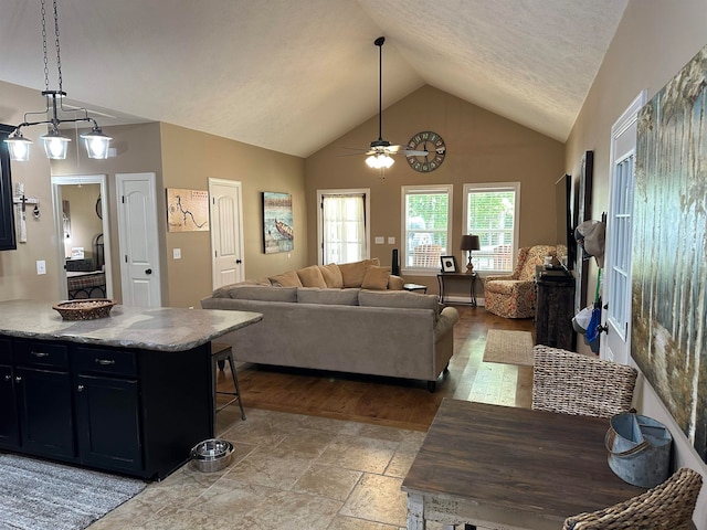 living room with high vaulted ceiling, light hardwood / wood-style flooring, ceiling fan, and a textured ceiling