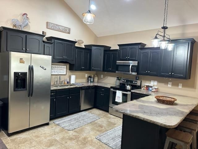 kitchen featuring stainless steel appliances, decorative light fixtures, kitchen peninsula, sink, and light stone countertops