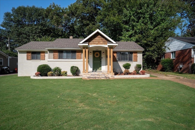 view of front of property with brick siding, a front yard, and a shingled roof