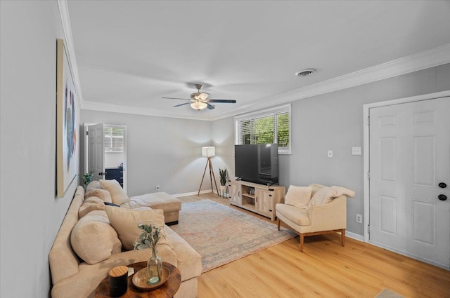 living room featuring visible vents, baseboards, light wood-style floors, and ornamental molding