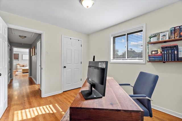 home office featuring attic access, light wood-type flooring, and baseboards