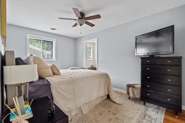 bedroom with visible vents, a ceiling fan, baseboards, and wood finished floors