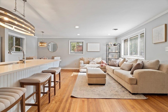 living area featuring light wood-style flooring, plenty of natural light, and ornamental molding