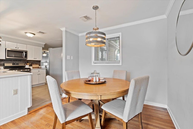 dining space featuring light wood-style flooring, baseboards, visible vents, and ornamental molding