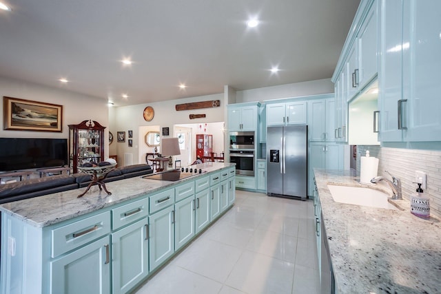 kitchen with light stone countertops, stainless steel appliances, sink, a kitchen island, and decorative backsplash