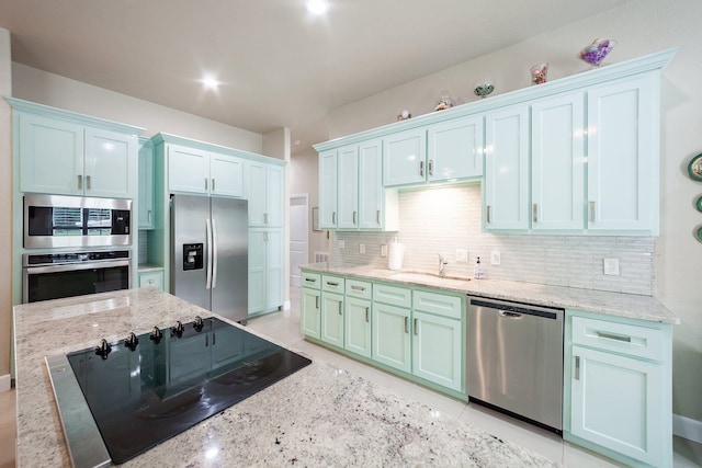 kitchen featuring backsplash, stainless steel appliances, sink, light stone countertops, and light tile patterned flooring