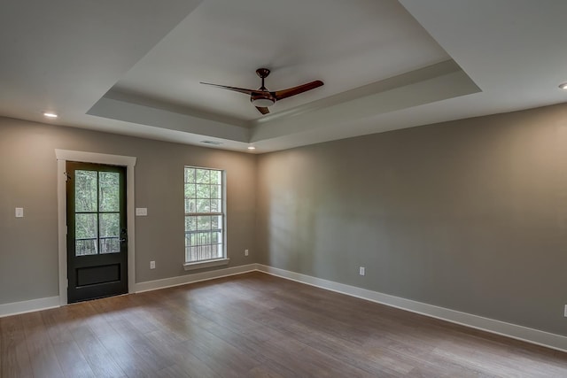 spare room with ceiling fan, wood-type flooring, and a tray ceiling