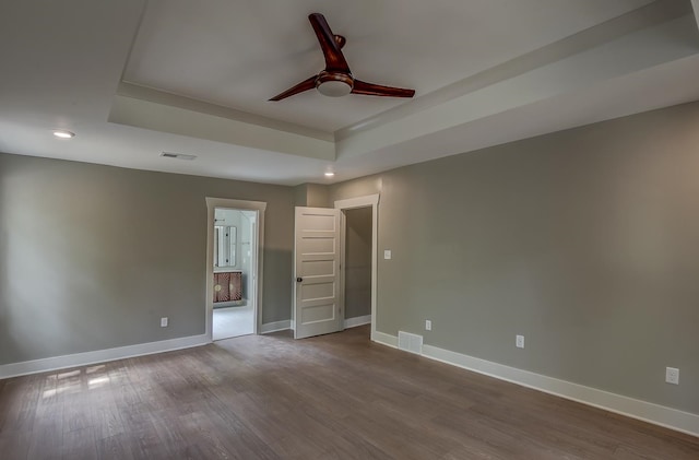 interior space with a raised ceiling, hardwood / wood-style floors, and ceiling fan